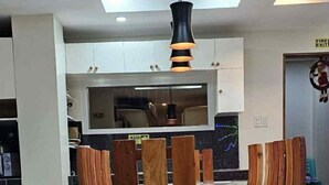 Ein Essbereich mit Holztisch und Stühlen, im Hintergrund eine moderne Küche und eine Decke mit eingelassener Beleuchtung.