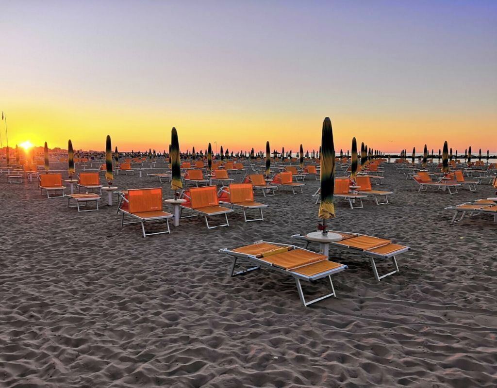 Ein Strand mit Reihen von Liegestühlen und Sonnenschirmen, die in einem Muster angeordnet sind.
