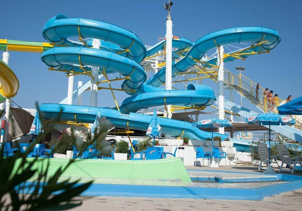 A water park with multiple water slides and a seating area with chairs and umbrellas.