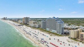 Ein Hotel an der Küste mit mehreren Gebäuden, einem Strand mit Sonnenschirmen und Badegästen sowie freiem Blick auf den Ozean.