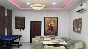 A room with a ping pong table, a round table with chairs, and artwork on the walls. - LUXURY 4BED APARTMENT IKOYI (Lagos)