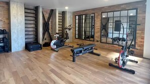 Uma academia ampla com piso de madeira, equipamentos de exercício e grandes janelas.