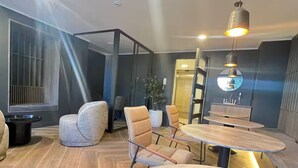 Um interior moderno com uma mesa redonda e quatro cadeiras, uma planta em vaso e um espelho grande na parede.
