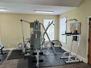 A gym with various exercise equipment, including a bench press, a leg press, and a cable machine.