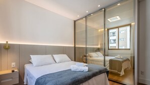 Et moderne hotelværelse med en stor seng, et natbord og et spejl.