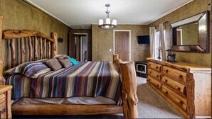 Une chambre à coucher au style rustique, avec un lit en bois, une couvre-lit à rayures, une commode en bois et un miroir.