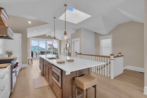 A spacious kitchen with a large island, pendant lighting, and a view to the outside. - BRAND NEW GOLDCOAST SINGLE (Ocean City)
