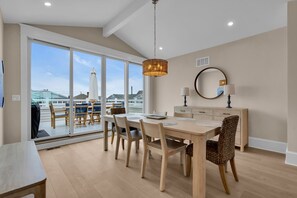 A dining area with a large table, chairs, a chandelier, a mirror, and a view through a glass door. - BRAND NEW GOLDCOAST SINGLE (Ocean City)