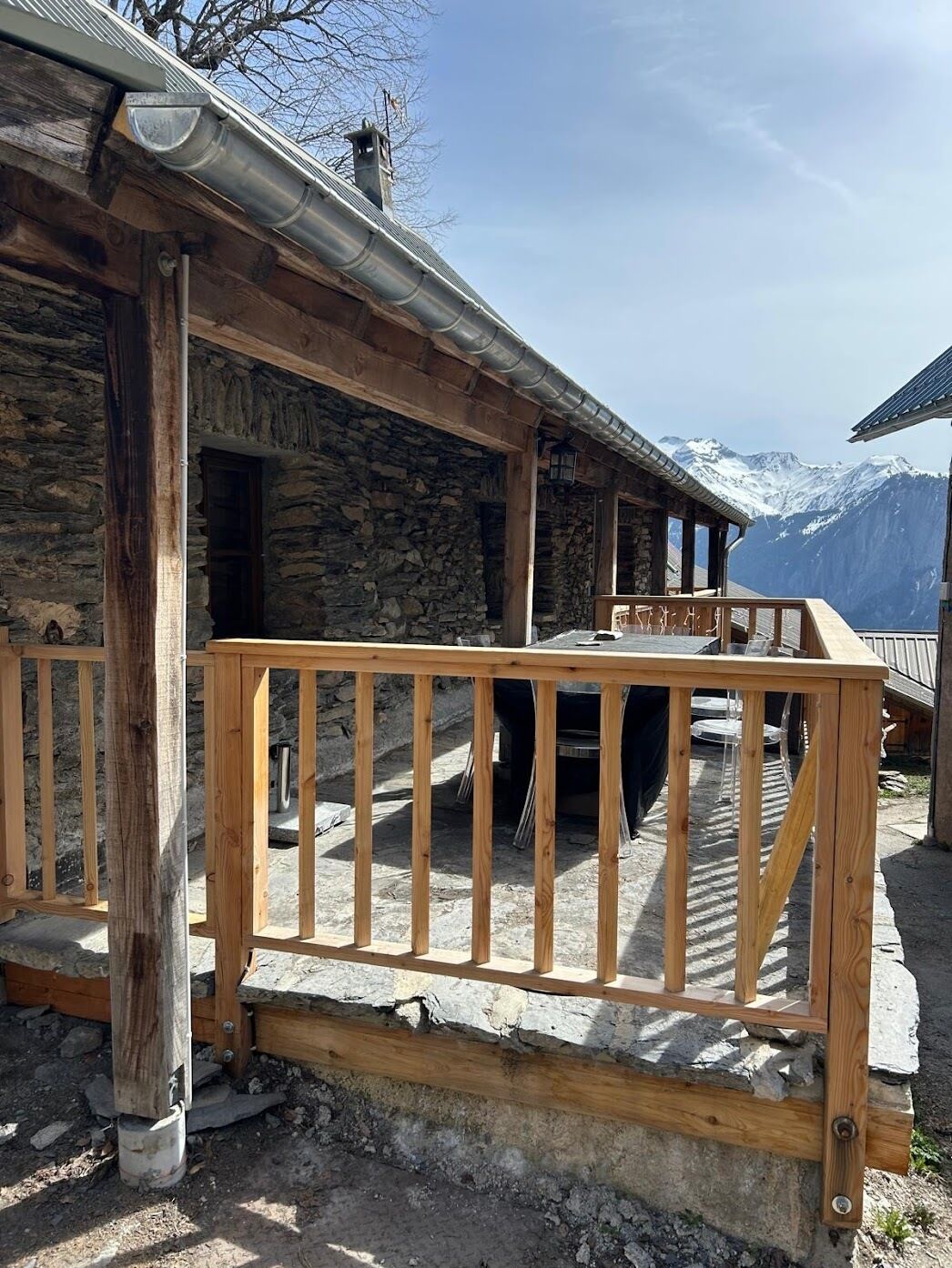 Un edificio de piedra con una terraza de madera y techo de metal.