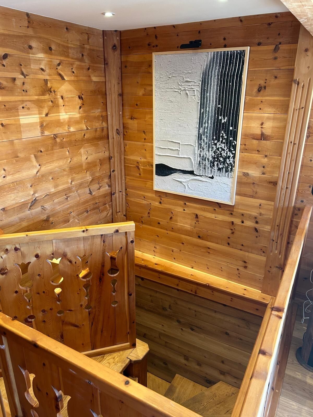 A wooden interior with a framed abstract painting on the wall.