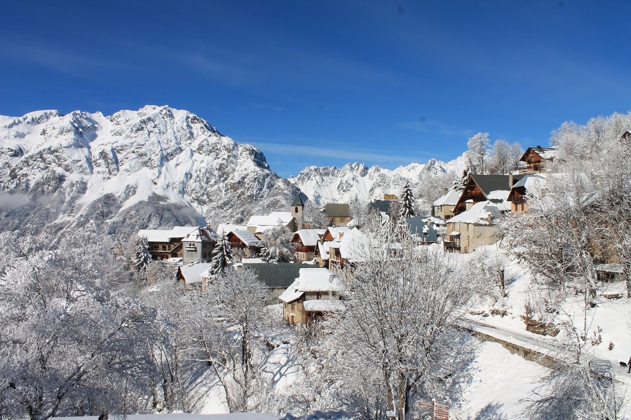 A snow-covered mountain village with traditional wooden houses and a clear blue sky.