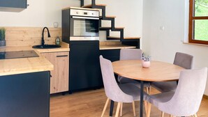 Une cuisine compacte dotée d’un four encastré, d’un évier et d’un coin repas avec une table ronde et quatre chaises.