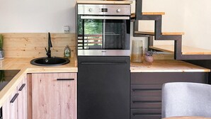 Une cuisine compacte équipée d’un four encastré, d’un évier et d’un petit réfrigérateur.