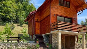 Une cabane en bois avec des fondations en pierre, une terrasse en bois et un mur en pierre agrémenté de plantes en pot.