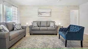 Un soggiorno con un divano grigio, una poltrona blu e un tappeto decorato.