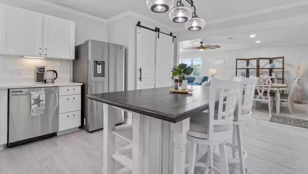 Een moderne keuken met witte kasten, een roestvrijstalen koelkast en een donker houten kookeiland.