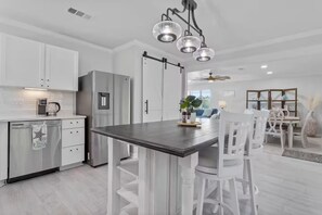 Una cocina moderna con armarios blancos, un refrigerador de acero inoxidable y una isla de madera oscura.
