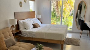 A modern bedroom with a bed, a sofa, a coffee table, and a view of the outdoors. - Comfortable and spacious room w/alberca (Cancún)