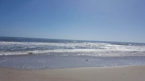Una playa con olas, cielo despejado y orilla arenosa.