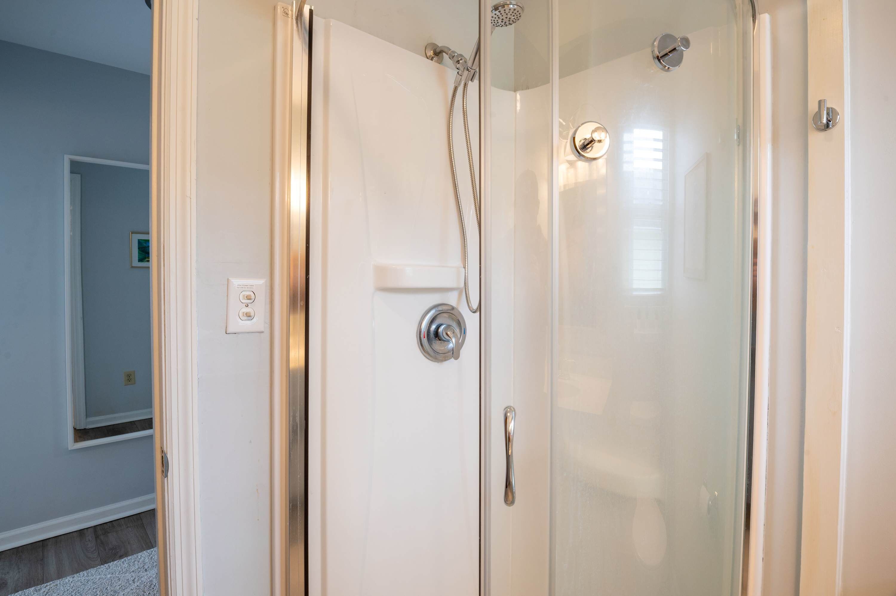Une douche fermée par des parois en verre, dotée d’une poignée chromée et d’un panneau de commande.