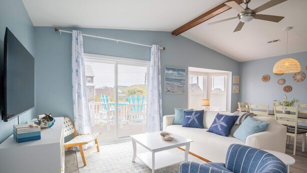 A living room with a white sofa, blue armchairs, a coffee table, a TV, and a ceiling fan. - Great Catch - Double Duplex - Dogs Allowed - Wraparound Deck (North Topsail Beach)