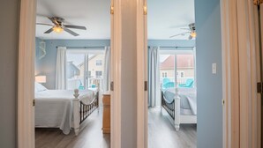A bedroom with two beds, a ceiling fan, and a view of the outside. - So Free - Dogs Allowed - Walk to Beach (North Topsail Beach)
