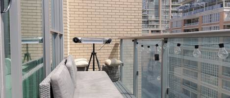 A balcony with a sofa, a tripod, and a trash bin.