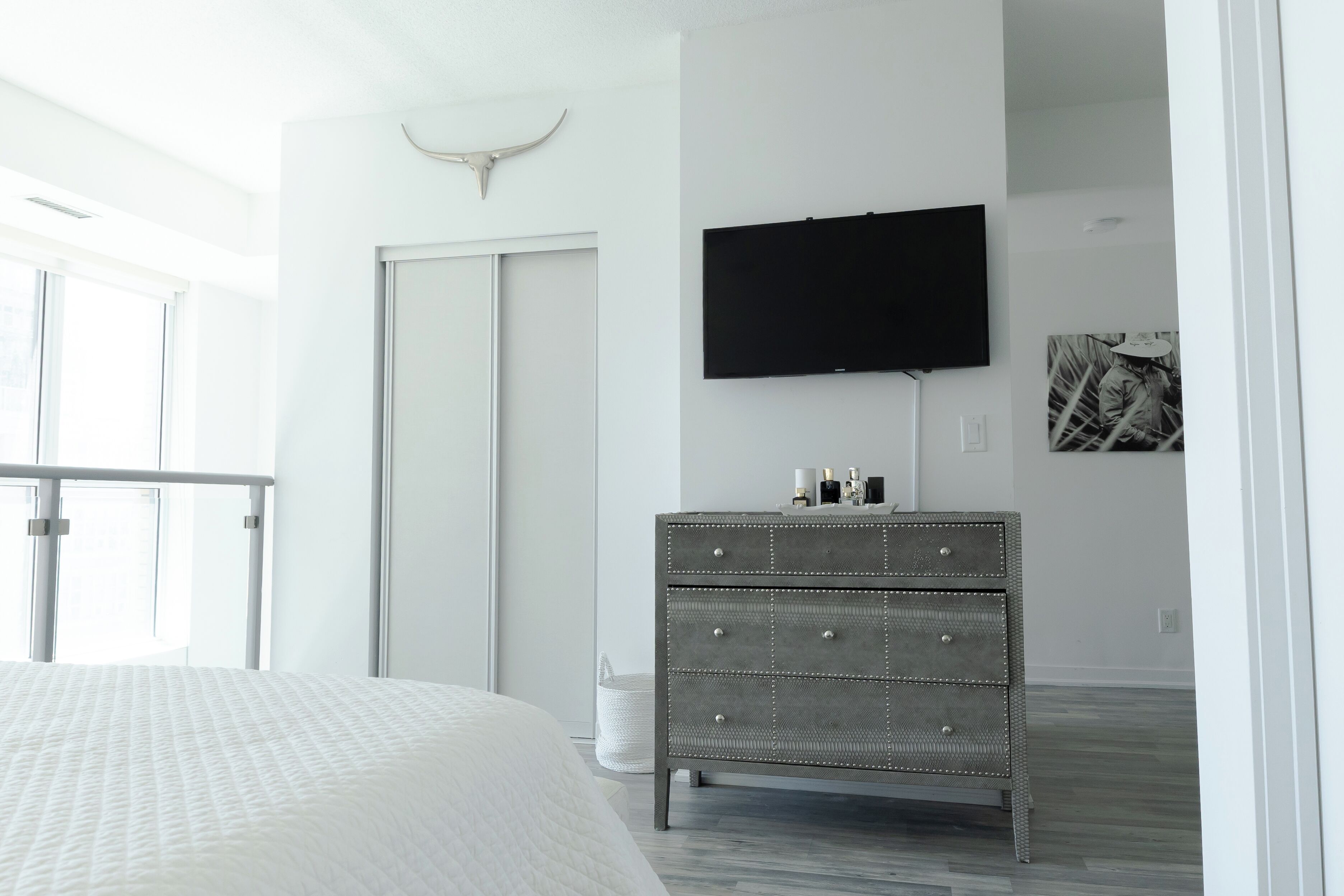 Ein Schlafzimmer mit Bett, Schminktisch, Fernseher und einer Tür mit Kuh-Dekoration.