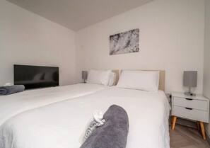 A hotel room with a large bed, a flat-screen TV, a bedside table with a lamp, and a wall-mounted artwork. - Luxury City Flat ✦ Steps to O2 Academy & Dining (Birmingham)