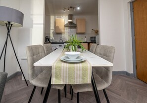 A dining area with a table set for two, a potted plant, and a lamp. - Luxury City Flat ✦ Steps to O2 Academy & Dining (Birmingham)