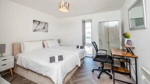 Un dormitorio moderno con una cama grande, un escritorio y una silla.