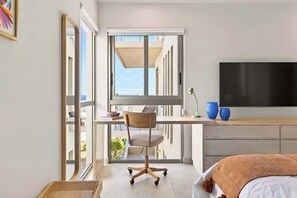 Une chambre moderne avec une grande fenêtre, un bureau, une chaise, un lit et un téléviseur.