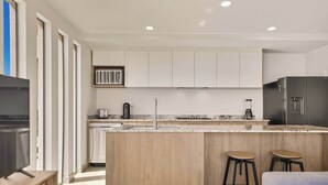 Una cocina moderna con una isla central, taburetes de bar y un horno empotrado.