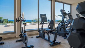 Un gimnasio con máquinas de cardio y amplios ventanales con vistas panorámicas.