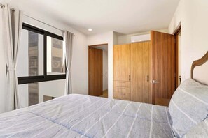 Een slaapkamer met een bed, een houten garderobe en een raam met gordijnen.