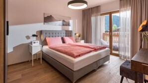 Quarto moderno com cama, mesa de cabeceira, luminária e vista para o exterior.
