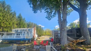 Une terrasse avec des sièges extérieurs, un belvédère blanc et un grand arbre.