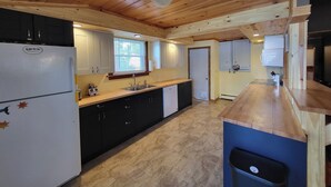 Une cuisine compacte avec des poutres en bois au plafond, un évier encastré et un réfrigérateur.