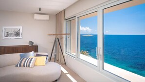 Una habitación moderna con un sofá curvo, un telescopio y un amplio ventanal con vistas al océano.