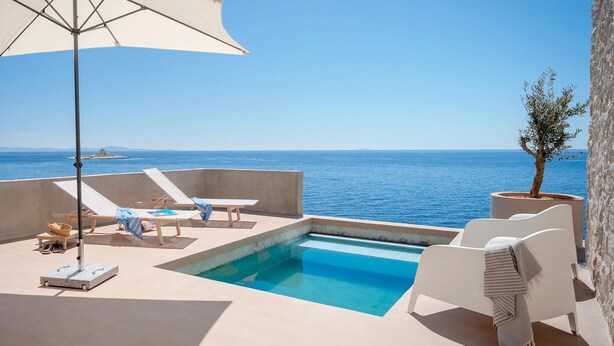 Zona de piscina en la azotea con sillones de descanso, una piscina pequeña y vista al mar.