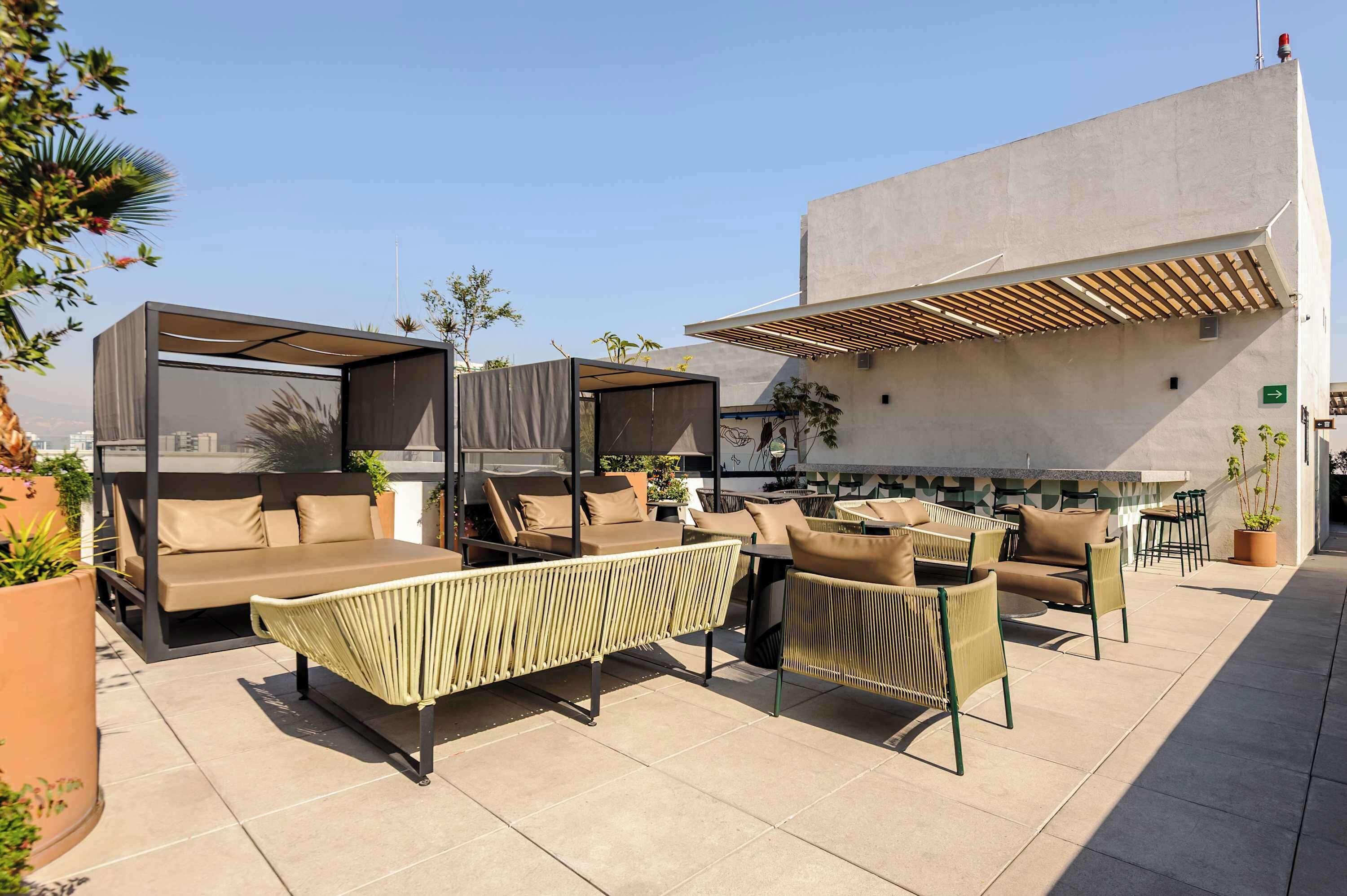 A rooftop patio with outdoor seating, including sofas and chairs, and a pergola structure.
