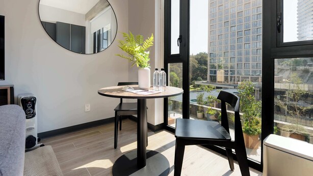 A modern room with a round table, a potted plant, and a large window offering a city view. - w* | Engaging Loft in the Heart of Interlomas (Naucalpan de Juárez)