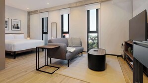 Une chambre d’hôtel moderne comprenant un lit, un canapé, une petite table, une table basse ronde et un téléviseur.