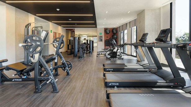 Een moderne sportschool met diverse fitnessapparaten, waaronder loopbanden en krachttoestellen.