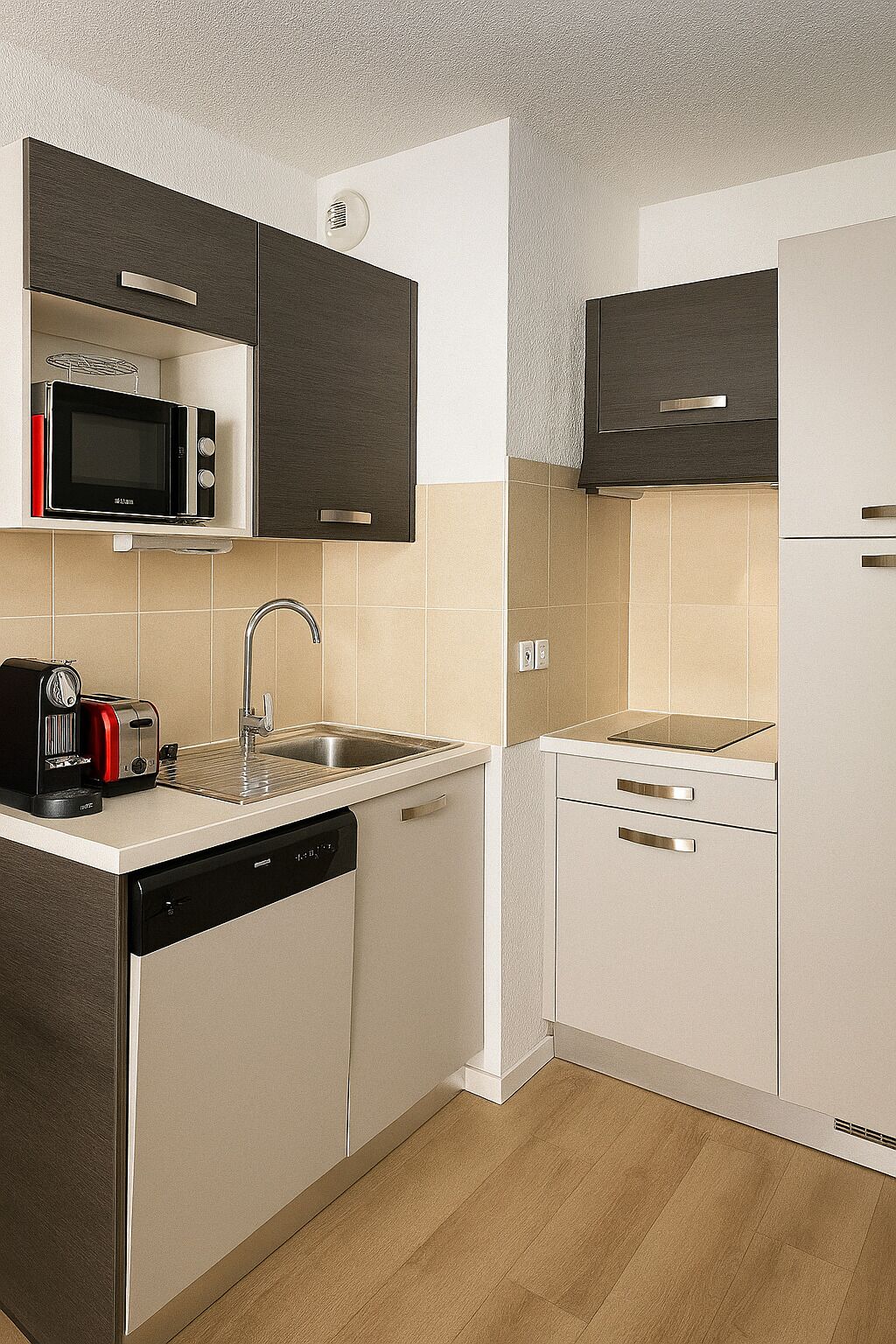 A compact kitchen with a microwave, toaster, sink, and dishwasher.