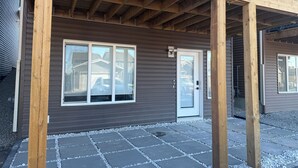 Une terrasse en bois avec un espace patio couvert, une porte et de grandes fenêtres.