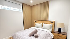 Une chambre moderne avec un lit, un mur recouvert de panneaux en bois, une table de chevet et une fenêtre.
