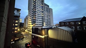 Un edificio alto y moderno con varios pisos y balcones, ubicado en un entorno urbano con una calle en primer plano.