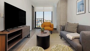 Un moderno salón con televisor de pantalla plana, un sofá, una mesa de centro y un balcón con vistas.