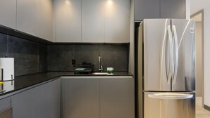 Una cocina moderna con armarios grises, un refrigerador de acero inoxidable y una encimera negra.